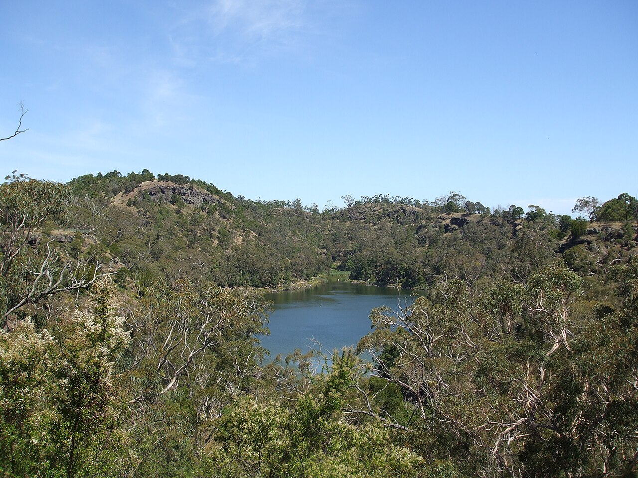A small lake in a volcanic crater surrounded by green woodland