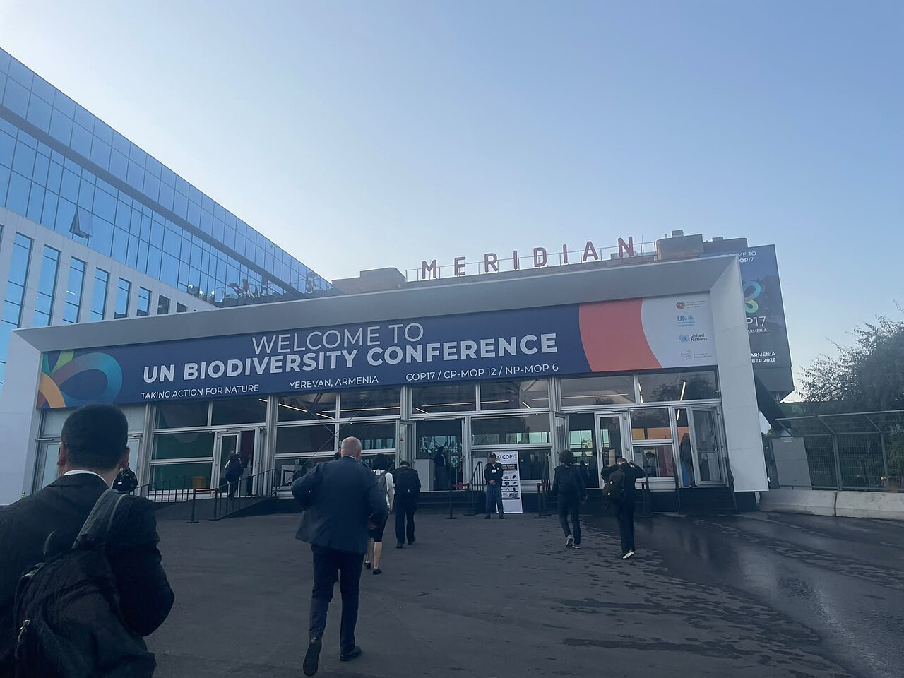 Delegates walking toward the entrance of the Meridian Expo Centre under a banner reading Welcome to UN Biodiversity Conference