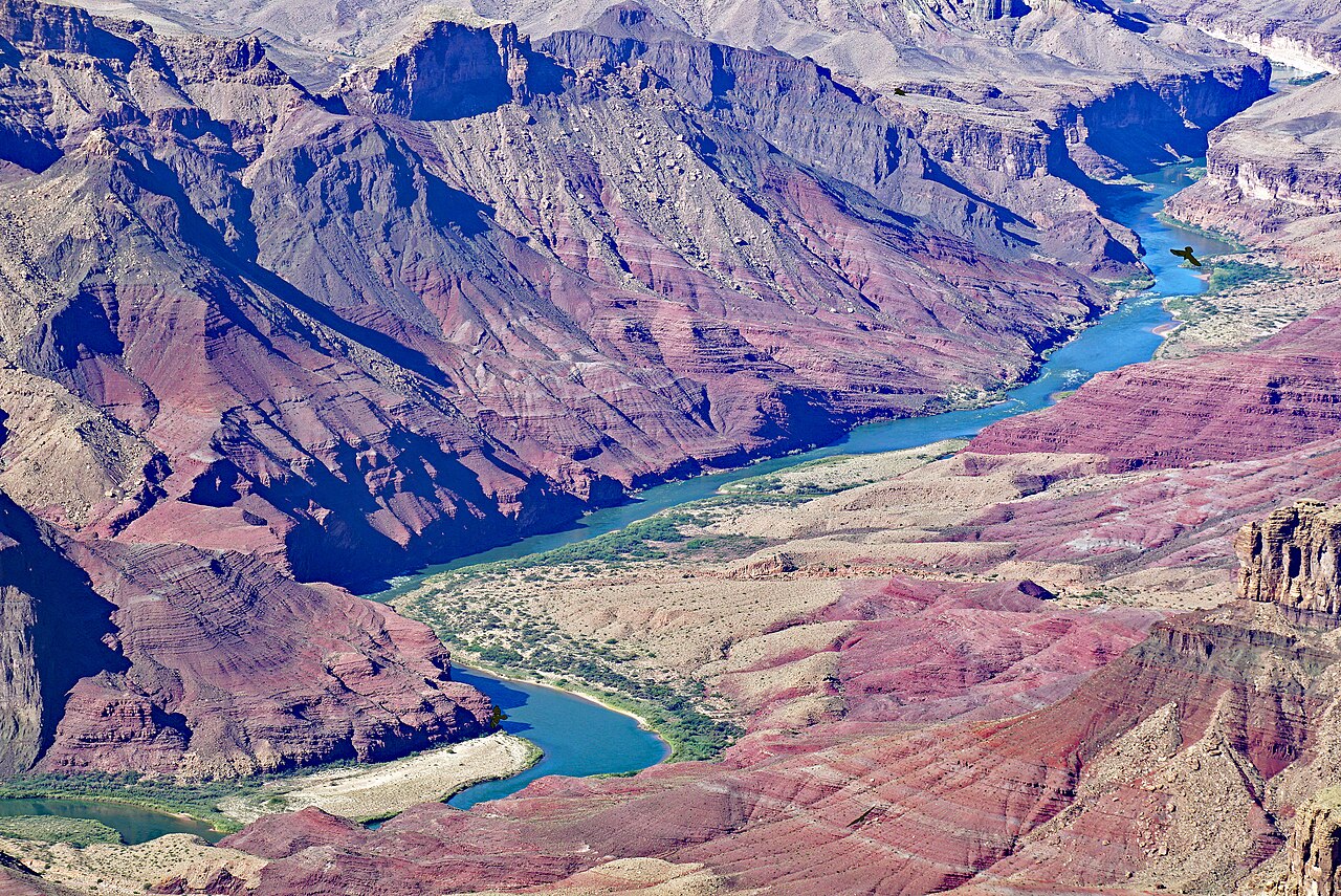 The Colorado River winding through deep red and purple canyon walls