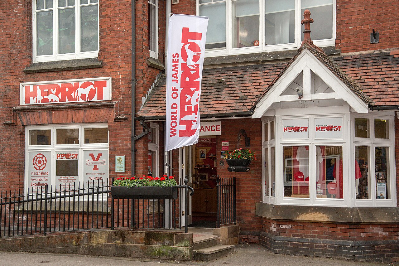 A red-brick house with white bay windows and a World of James Herriot banner