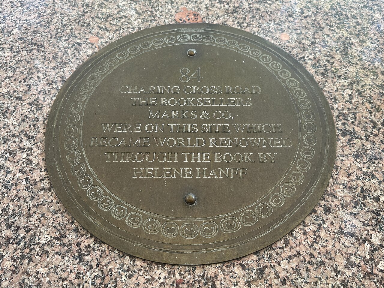 A round bronze plaque reading 84 Charing Cross Road, the booksellers Marks and Co. were on this site, which became world renowned through the book by Helene Hanff