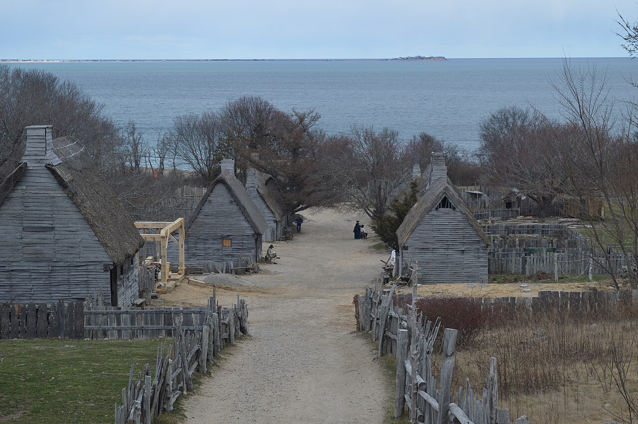 Wooden houses with thatched roofs along a dirt street running down toward the sea